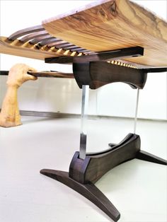 a wooden table with a glass top on it's legs and an arm holding a knife