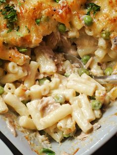 a white plate topped with macaroni and cheese covered in meat, veggies and sauce