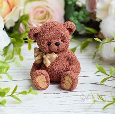 a brown teddy bear sitting next to flowers