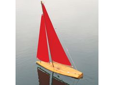 a red sailboat floating on top of a body of water