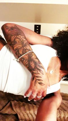 a woman laying on top of a bed with tattoos on her arm and leg,