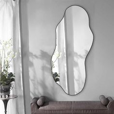 a living room with a couch, mirror and potted plant