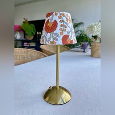 a lamp that is sitting on top of a white table cloth covered table with chairs in the background