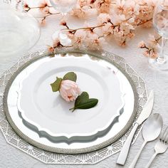 a white plate topped with a pink flower next to silverware and utensils