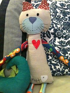 a cat stuffed animal sitting on top of a bed next to pillows and pillow cases