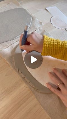 a woman is making something with her hands on the paper and using a pen to draw it