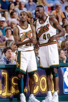 two basketball players standing next to each other in front of a crowd at a game