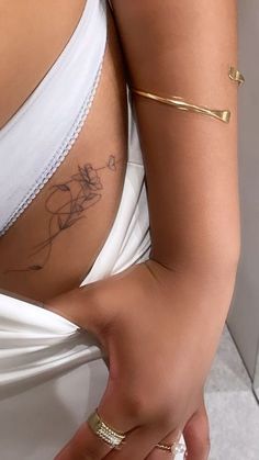 a woman's stomach with tattoos on her left side and right hand in the air