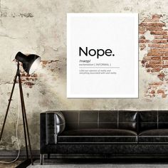 a living room with a black couch and a white poster on the wall above it