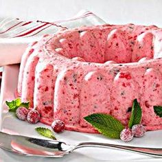 a bundt cake with raspberries and mints on the side next to a fork