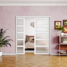 an empty room with pink walls and wooden flooring is pictured in this image, there are two planters on either side of the door