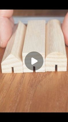 a person holding a piece of wood on top of a wooden table