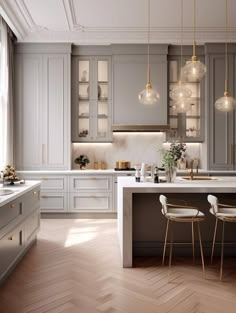 a large kitchen with white cabinets and gold accents on the counter tops, along with two bar stools