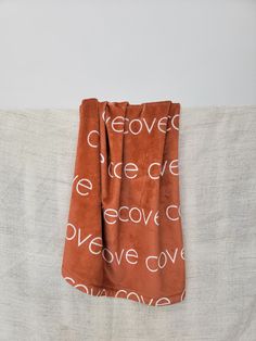 an orange towel with white words on it sitting on top of a bed next to a pillow