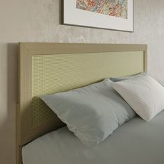 a bed with two pillows on top of it and a painting above the headboard