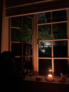 a lit candle sitting on top of a window sill