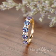 a yellow gold ring with purple and white stones on the side, sitting on a wooden surface