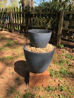 two large bowls are stacked on top of each other in the grass near a fence