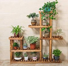 a wooden shelf filled with potted plants on top of a tiled floor