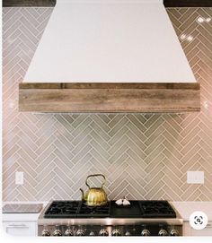 a tea kettle sitting on top of a stove next to a wall mounted range hood