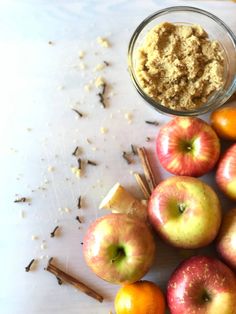 apples, cinnamon sticks and an orange on a table