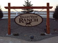 a sign for valley view ranch in front of a fenced area with pine trees