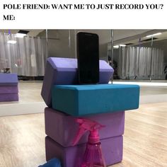 a cell phone sitting on top of a stack of purple and blue blocks with a pink spray bottle next to it