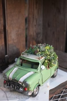 an old green car with succulents on the roof is sitting on top of a piece of paper