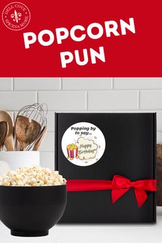 the popcorn pun gift box is next to a bowl of popcorn and spatulas