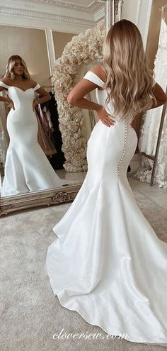 a woman in a white wedding dress looking at her reflection