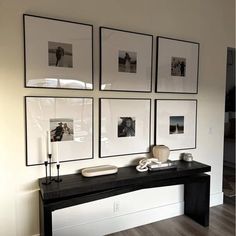 a black table topped with pictures next to a white wall