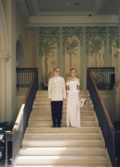 a man and woman in formal wear standing on the stairs next to eachother