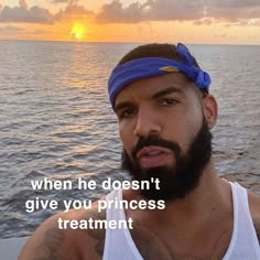 a man with a bandana on his head standing in front of the ocean at sunset