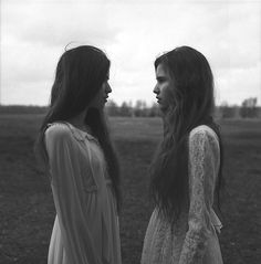 two women standing next to each other in a field