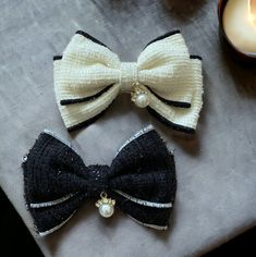 two bows with pearls on them sitting next to a candle