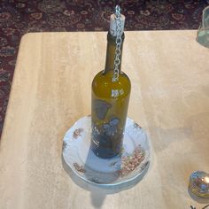 a wine bottle sitting on top of a plate with a chain hanging from it's neck