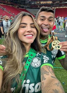 a man and woman posing for a photo at a sporting event