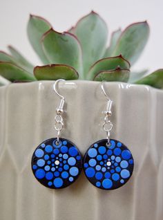 a pair of blue and black earrings sitting on top of a potted plant