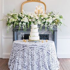 a table with a cake and flowers on it in front of a fire place mantle