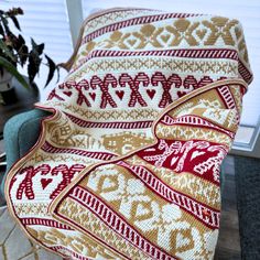 a couch covered in a blanket sitting on top of a wooden floor next to a window