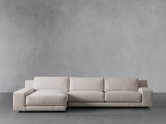 a white couch sitting on top of a cement floor next to a gray concrete wall