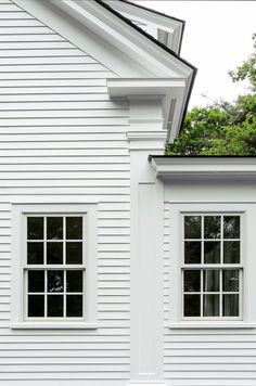 two windows on the side of a white house