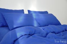 a bed with blue sheets and pillows on it