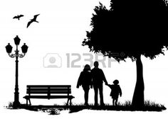 an image of a family walking in the park silhouetted against a tree and street light