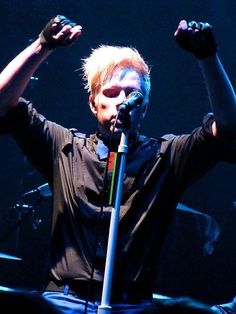 a man with his hands in the air while singing into a microphone at a concert