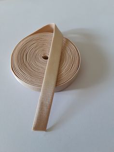 a roll of tan colored cloth tape on a white surface with a single piece of ribbon in the middle