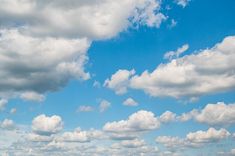 the sky is filled with white clouds and green grass, as well as sheep grazing in an open field