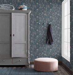 a room with blue wallpaper and a white armoire in the corner next to a window