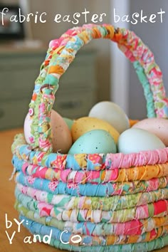 a basket filled with lots of different colored eggs sitting on top of a wooden table