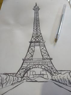 a drawing of the eiffel tower on paper with a pen next to it